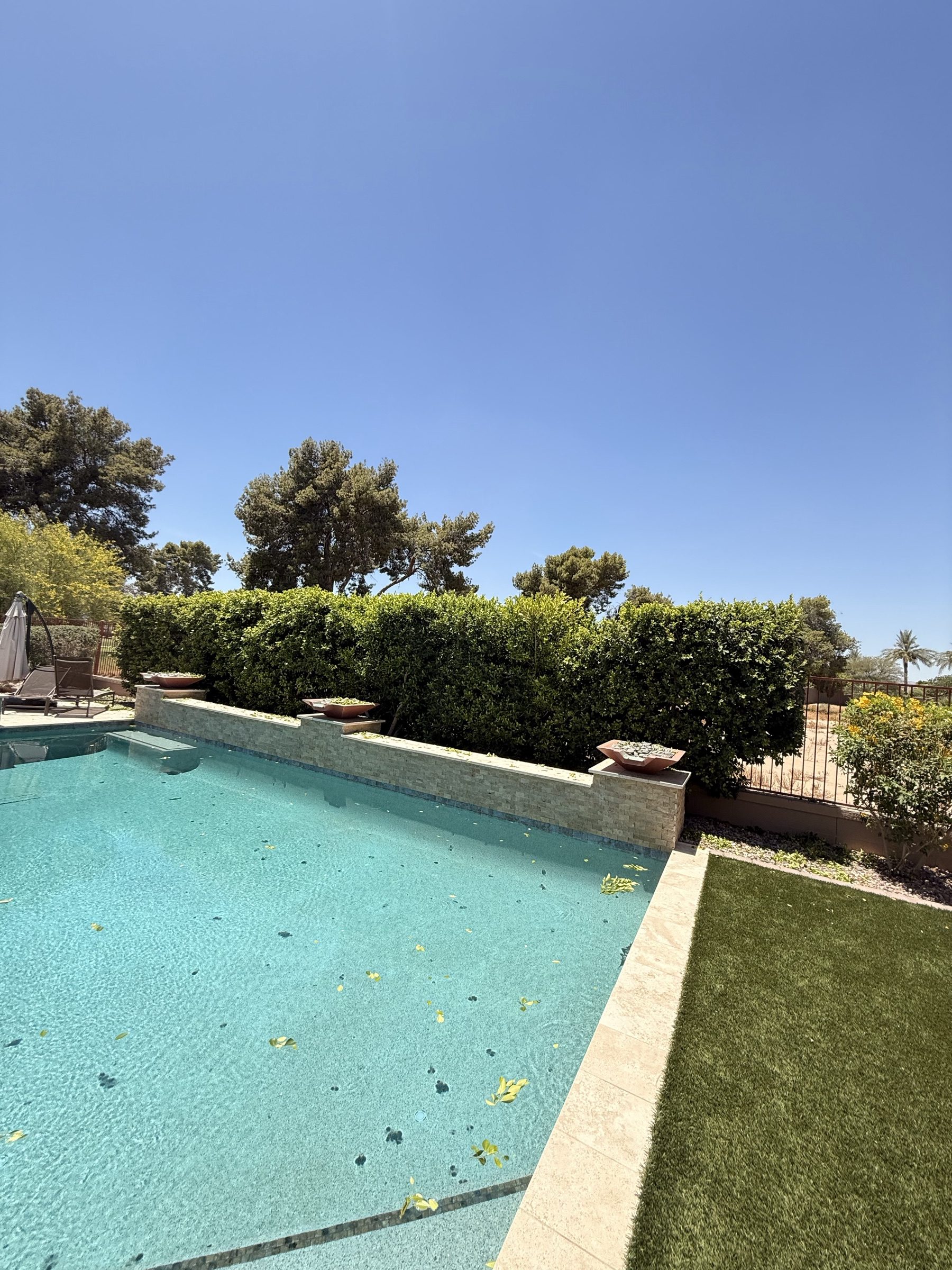 Paradise Valley estate pool with stacked travertine wall, copper bowls and manicured hedge