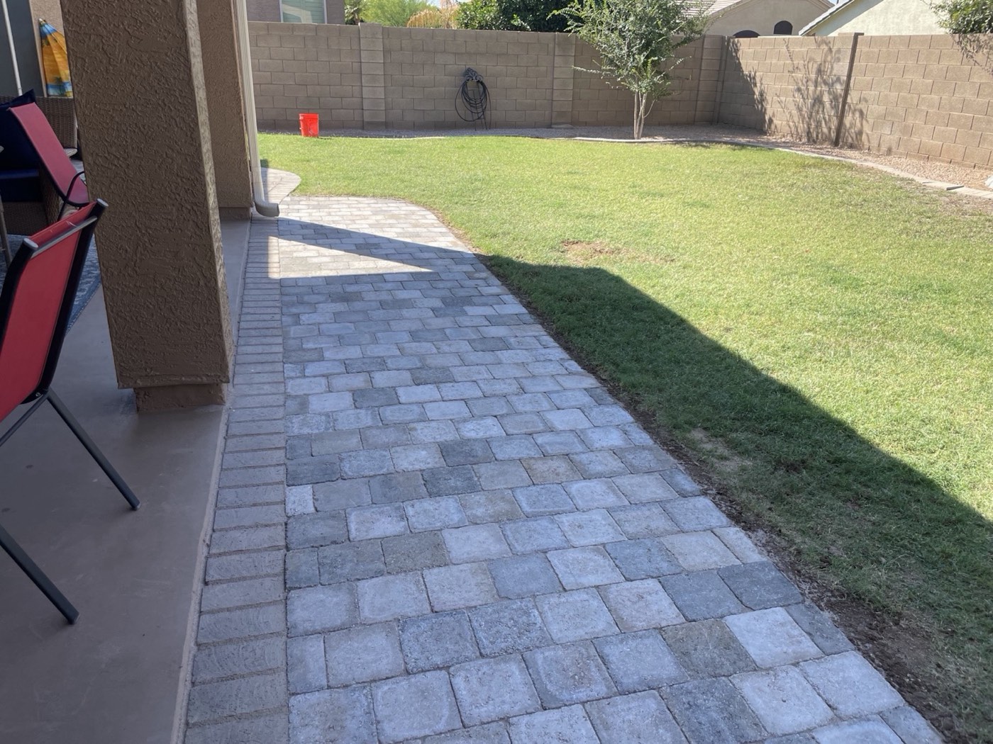 Backyard paver walkway beside lawn